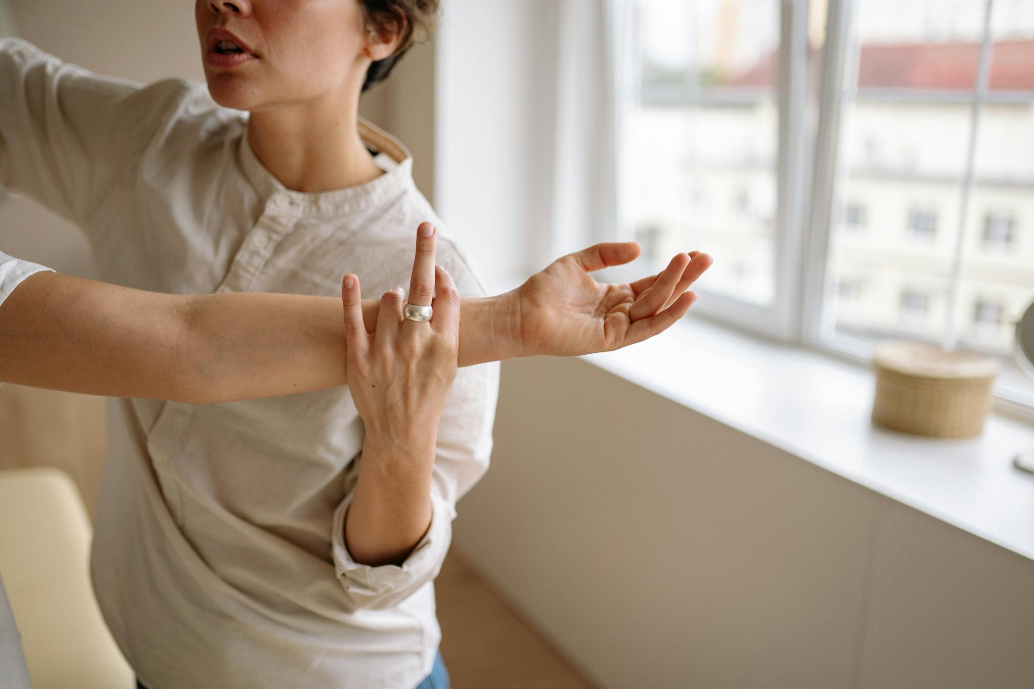 Physical therapist stretches a woman's arm in a sunny room.